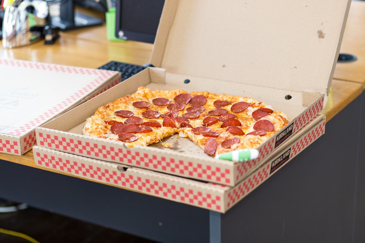 afbeelding over hardwerkende manager die pizza's eet op het werk